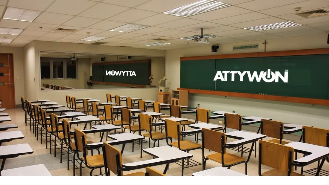 An empty classroom with rows of desks facing a chalkboard and a large mirror reflecting the room; text on board and mirror.
