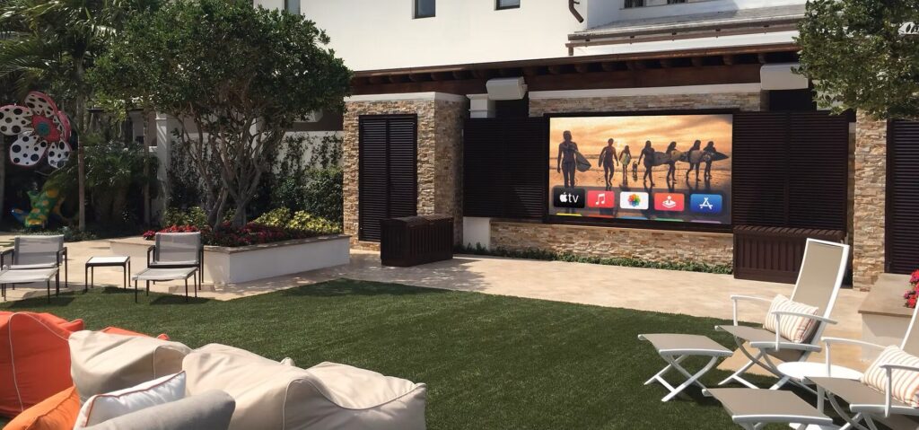 An outdoor patio with seating and a large flat-screen TV displaying streaming apps and a TV show.