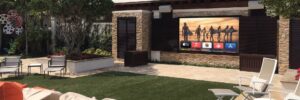 An outdoor patio with seating and a large flat-screen TV displaying streaming apps and a TV show.