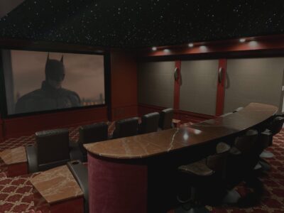Home theater room with tiered seating, red carpet, and a large screen displaying a Batman movie scene.