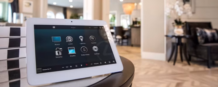 A tablet displaying a smart home control interface sits on a table in a modern, well-lit living space.